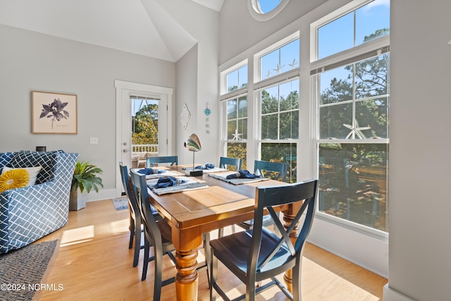 dining area featuring light wood-type flooring and vaulted ceiling