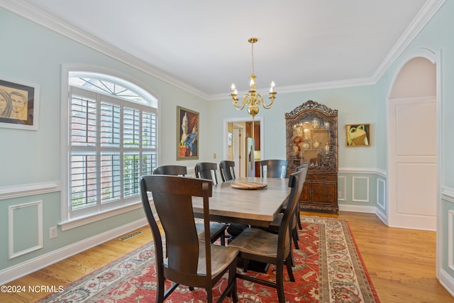 dining space with light wood-type flooring, a chandelier, and crown molding