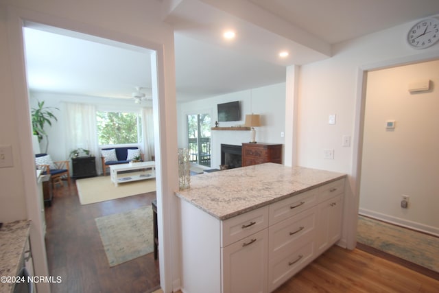 kitchen featuring ceiling fan, dark wood-type flooring, light stone counters, and white cabinets