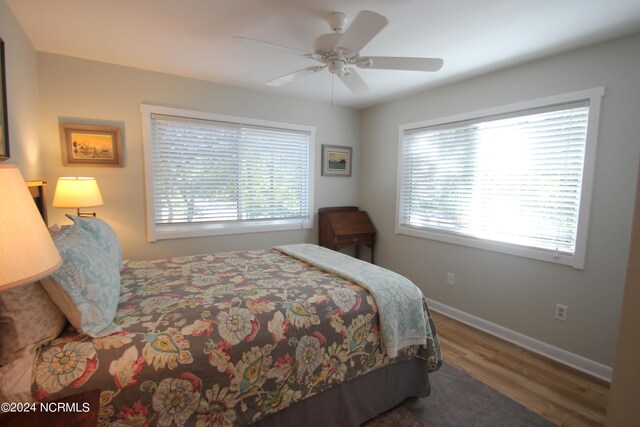 bedroom featuring multiple windows, hardwood / wood-style floors, and ceiling fan