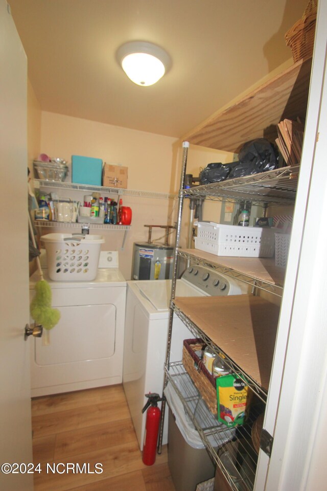 laundry area featuring water heater, light hardwood / wood-style flooring, and independent washer and dryer