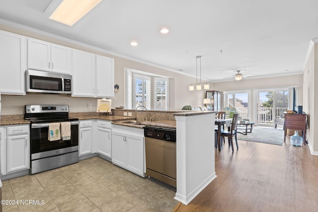 kitchen with stainless steel appliances, kitchen peninsula, plenty of natural light, and hanging light fixtures