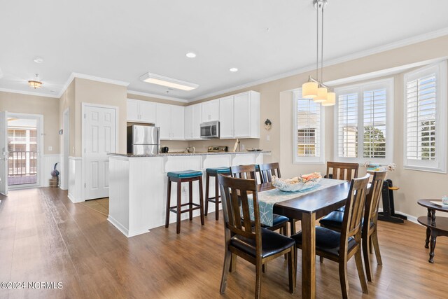 dining room with ornamental molding, hardwood / wood-style flooring, and a healthy amount of sunlight