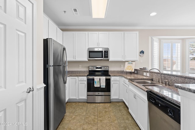 kitchen featuring ornamental molding, sink, white cabinetry, stainless steel appliances, and dark stone counters