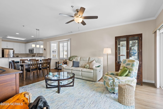 living room with ceiling fan, light wood-type flooring, and ornamental molding