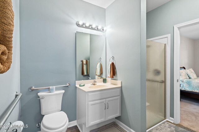 bathroom featuring a shower with shower door, vanity, and toilet