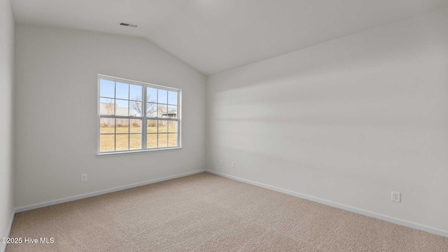 spare room with visible vents, baseboards, carpet, and vaulted ceiling