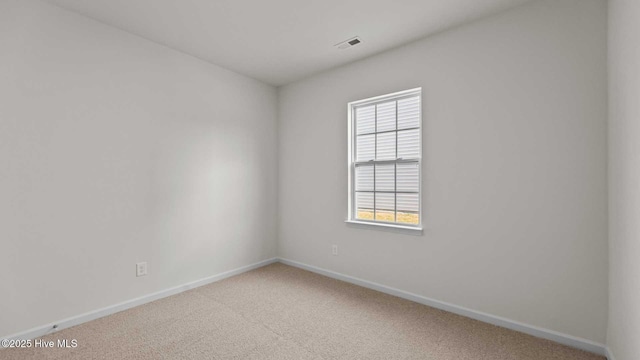 carpeted spare room featuring visible vents and baseboards