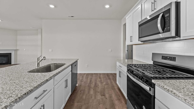 kitchen with dark wood-style floors, a sink, decorative backsplash, stainless steel appliances, and white cabinets