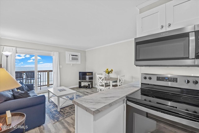 kitchen featuring appliances with stainless steel finishes, light wood-style floors, a peninsula, open floor plan, and white cabinetry