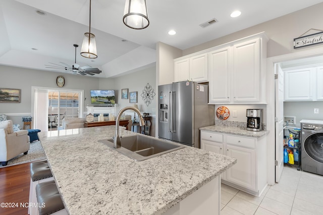 kitchen with sink, white cabinets, high end refrigerator, and washer / clothes dryer