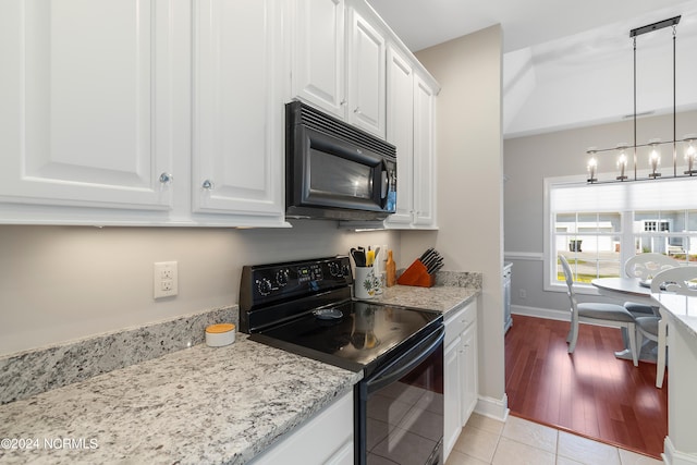 kitchen featuring black appliances, light stone countertops, white cabinets, pendant lighting, and light hardwood / wood-style flooring