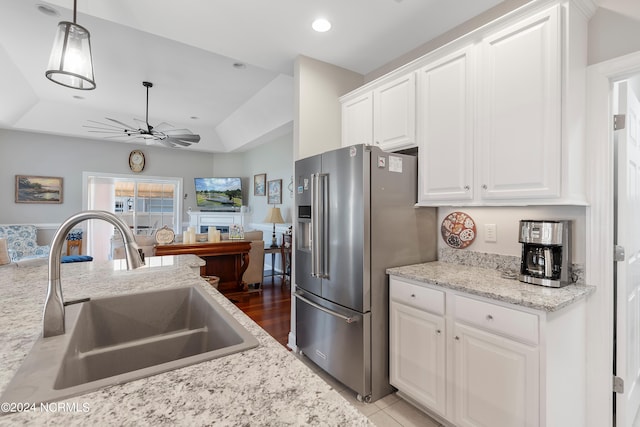 kitchen with a tray ceiling, decorative light fixtures, sink, high end fridge, and white cabinets