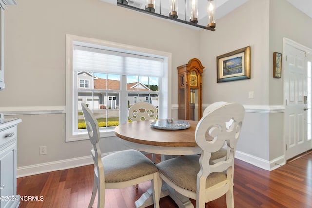 dining space with dark hardwood / wood-style floors and an inviting chandelier