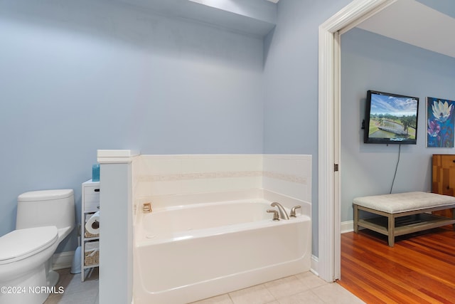 bathroom with a washtub, hardwood / wood-style flooring, and toilet