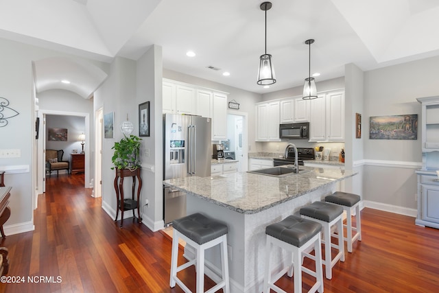 kitchen with stainless steel appliances, an island with sink, dark hardwood / wood-style flooring, and white cabinetry