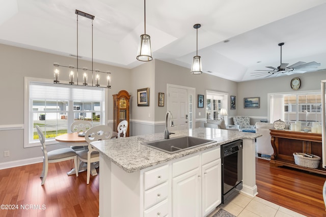 kitchen featuring light wood-type flooring, sink, white cabinetry, decorative light fixtures, and dishwasher