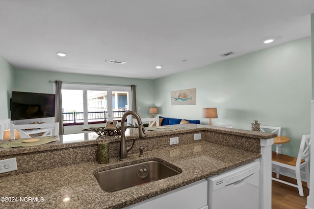 kitchen featuring wood-type flooring, dishwasher, sink, and dark stone countertops