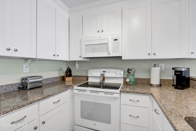 kitchen with crown molding, dark stone counters, white appliances, and white cabinetry