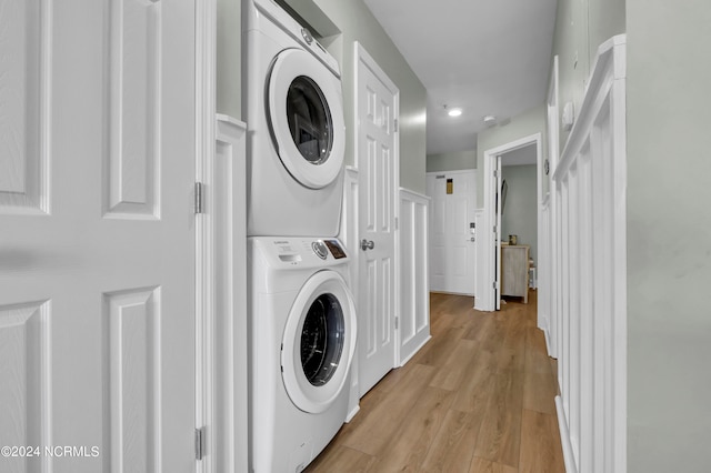 washroom with light hardwood / wood-style floors and stacked washer / drying machine