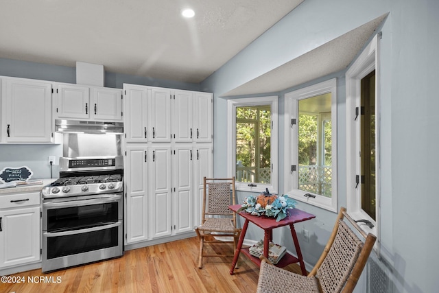 kitchen featuring light hardwood / wood-style floors, range with two ovens, and white cabinetry