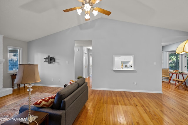 living room with light hardwood / wood-style floors, vaulted ceiling, and ceiling fan