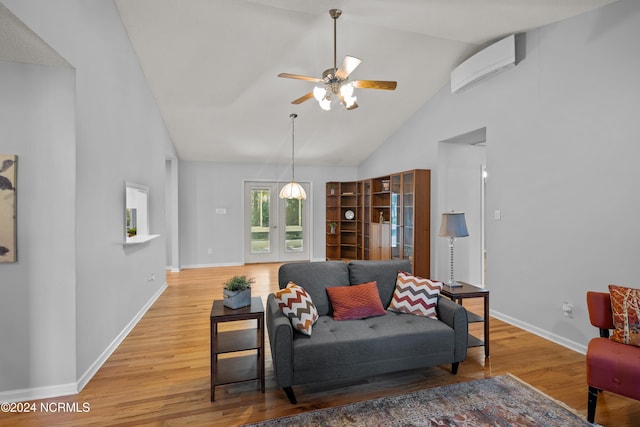 living room with a wall mounted air conditioner, ceiling fan, hardwood / wood-style floors, and high vaulted ceiling