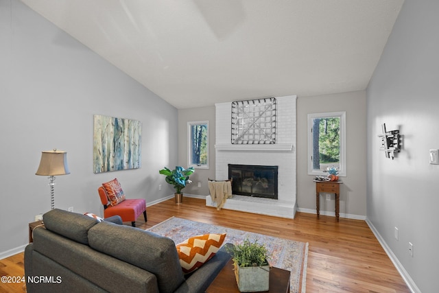 living room with a fireplace, hardwood / wood-style flooring, a wealth of natural light, and lofted ceiling