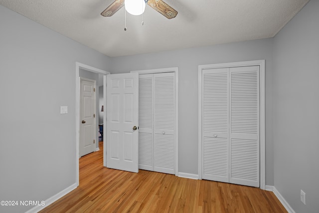 unfurnished bedroom featuring a textured ceiling, two closets, ceiling fan, and light hardwood / wood-style floors