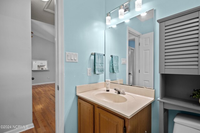 bathroom featuring a textured ceiling, vanity, hardwood / wood-style flooring, and toilet