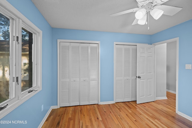 unfurnished bedroom featuring multiple closets, ceiling fan, and light wood-type flooring