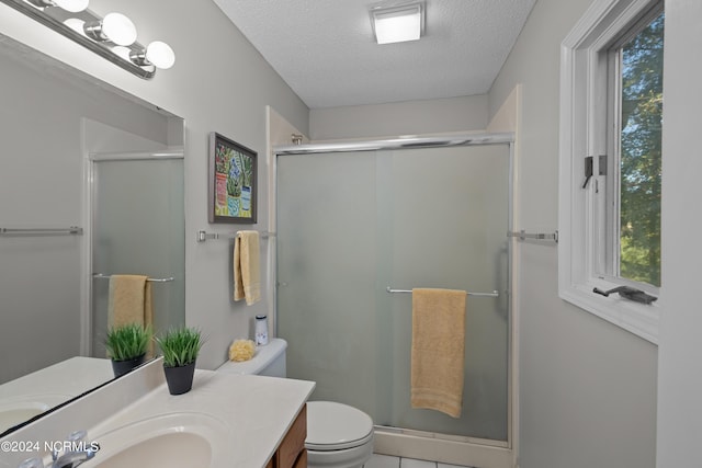 bathroom featuring vanity, toilet, a shower with door, and a textured ceiling