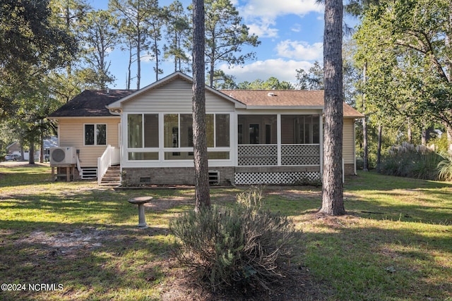 back of property with a sunroom, ac unit, and a yard