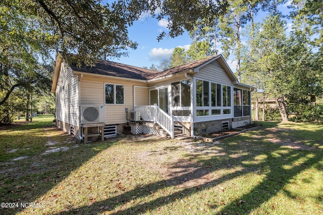 view of front of home with a sunroom, ac unit, and a front yard