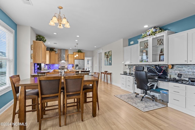 dining area featuring a notable chandelier, light hardwood / wood-style flooring, built in desk, and plenty of natural light