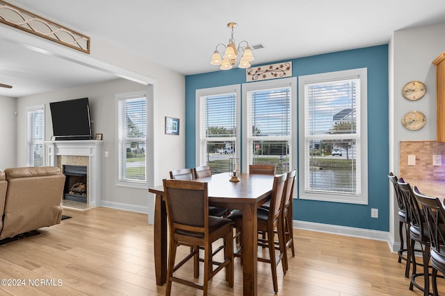 dining area featuring light hardwood / wood-style flooring, ceiling fan with notable chandelier, and a healthy amount of sunlight