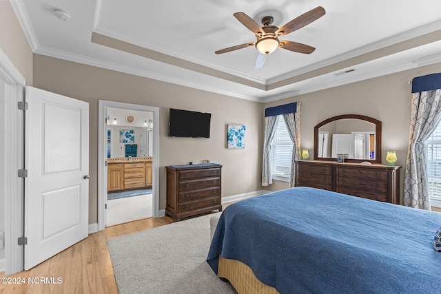 bedroom featuring light hardwood / wood-style floors, ensuite bath, a raised ceiling, ornamental molding, and ceiling fan