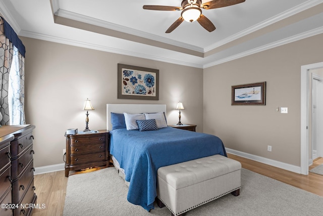 bedroom featuring ceiling fan, a tray ceiling, crown molding, and light hardwood / wood-style floors