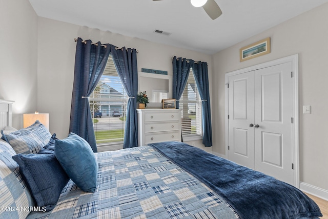 bedroom with light wood-type flooring, ceiling fan, and a closet