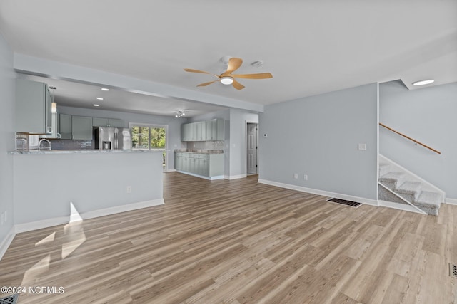 unfurnished living room featuring ceiling fan and light wood-type flooring