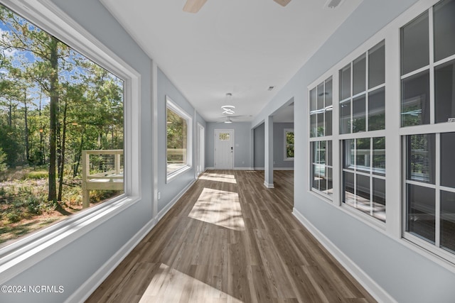 unfurnished sunroom featuring decorative columns and ceiling fan