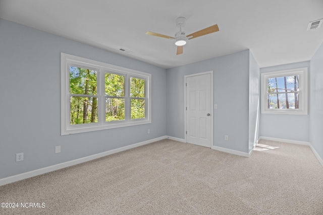 unfurnished bedroom with light carpet, multiple windows, and ceiling fan