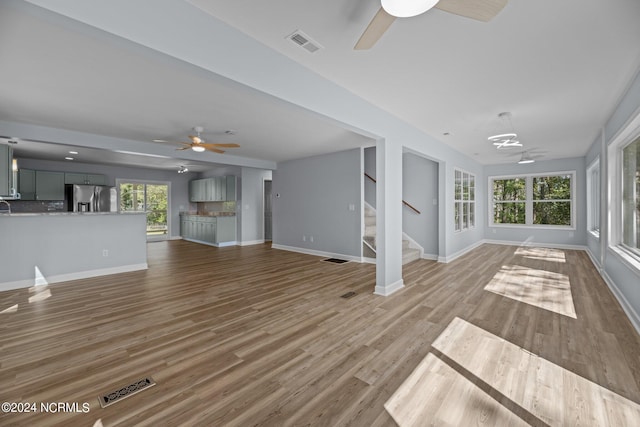 unfurnished living room with light hardwood / wood-style flooring, ceiling fan, and a healthy amount of sunlight