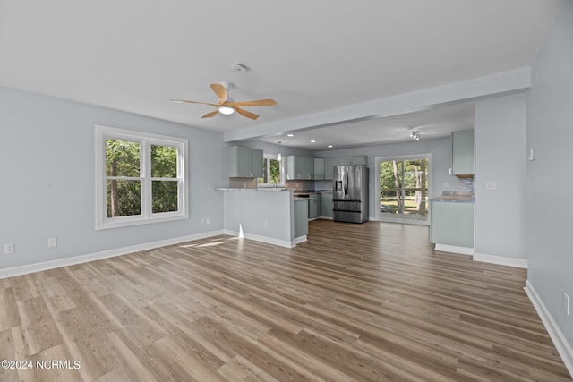 unfurnished living room with hardwood / wood-style flooring, plenty of natural light, and ceiling fan