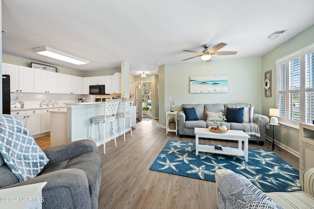 living room with light wood-type flooring and ceiling fan