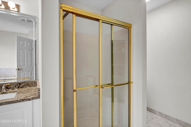 bathroom featuring a shower with shower door and vanity