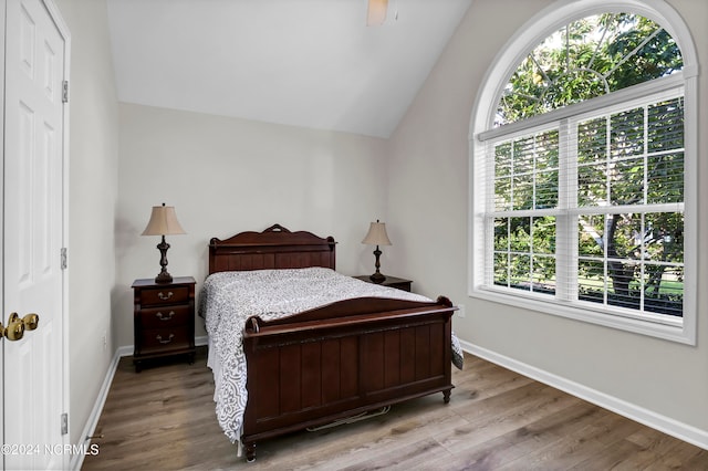 bedroom featuring lofted ceiling, hardwood / wood-style floors, and multiple windows