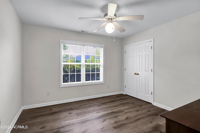 unfurnished bedroom with ceiling fan, a closet, and dark hardwood / wood-style flooring