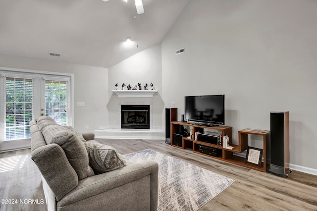 living room featuring high vaulted ceiling, a fireplace, ceiling fan, and hardwood / wood-style floors