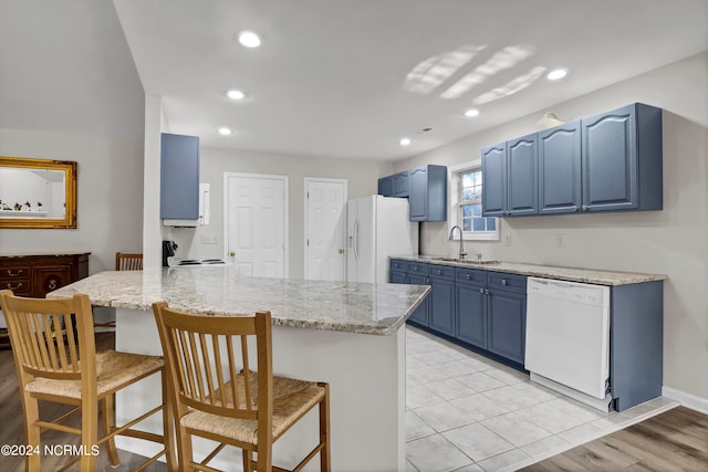 kitchen featuring blue cabinets, light wood-type flooring, kitchen peninsula, and white appliances